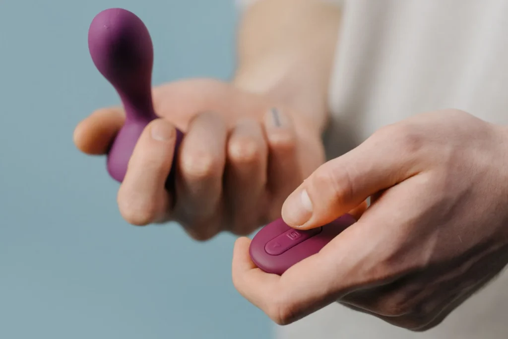 Två händer som håller en prostatavibrator och en fjärrkontroll.